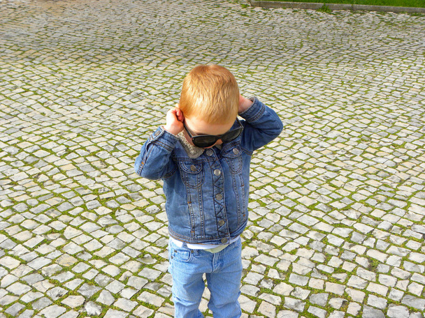    Cute boy with blond hair dresses in sunglasses. Boy playing with sunglasses                             - Fotoğraf, Görsel