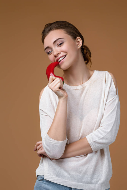 Portrait of pretty young woman biting chili pepper - Foto, Imagen