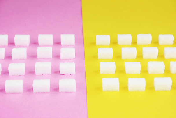cubes of white natural sweet refined sugar on pink yellow background - Φωτογραφία, εικόνα