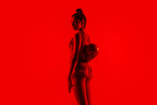 Young flexible female gymnast isolated on red studio background - Valokuva, kuva