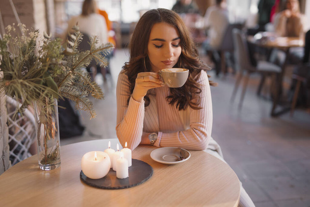 Portrait of young woman drinking coffee in a cafe - Фото, изображение