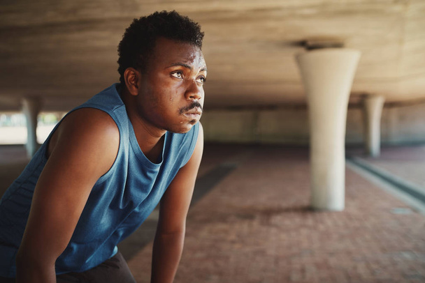 Portrait of tired fitness young african american man outdoors in the city catching breathe after a run - 写真・画像