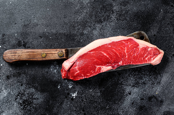 Rauwe biefstuk op een hakmes. Marmeren rundvlees. Zwarte achtergrond. Bovenaanzicht - Foto, afbeelding
