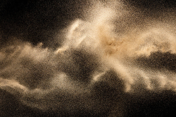 braun gefärbter Sand spritzt.Trockener Flusssand Explosion isoliert auf schwarzem Hintergrund. abstrakte Sandwolke. - Foto, Bild
