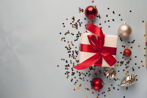 Kompozycja świąteczna na białym tle z białym pudełkiem z czerwoną wstążką z gałązkami jodły, zabawkami i przestrzenią do kopiowania gratulacji - Zdjęcie, obraz