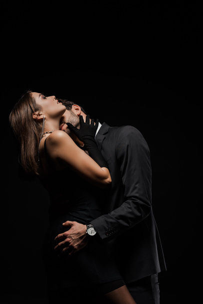 bearded man kissing attractive woman isolated on black  - Фото, изображение
