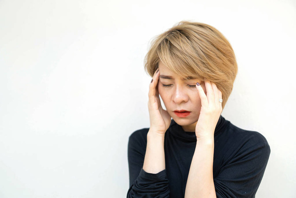 eine asiatische Frau mit goldenem Haar, die vorgibt, Kopfschmerzen zu haben. - Foto, Bild