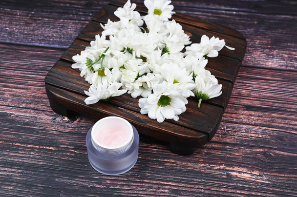 The concept of natural cosmetics. flowers and a jar of cream. heart-shaped chamomiles and a jar of cream. View from above. Natural cosmetic. place to record. - Photo, image