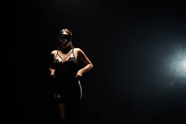 submissive and blindfolded girl in underwear standing on black with smoke  - Фото, зображення
