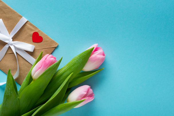 Horní pohled na tulipány s obálkou na modrém pozadí s kopírovacím prostorem - Fotografie, Obrázek