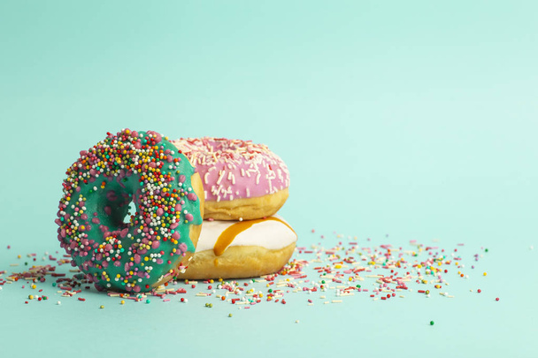 Donuts (Donuts) in verschiedenen Farben auf grünem Hintergrund - Foto, Bild