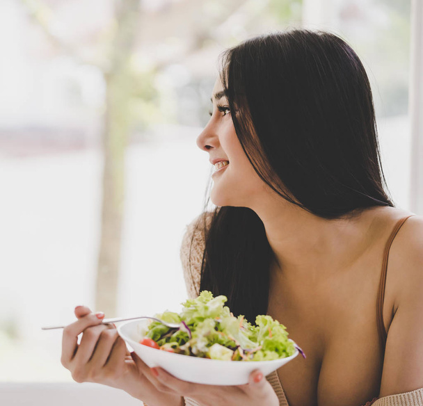 Healthy young woman is eating green salad for healthy lifestyle  - Photo, Image