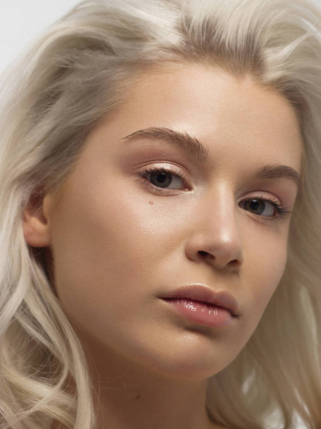 Closeup portrait of a woman with developing straight hair. Sweet tender young girl blonde. Natural lipstick, transparent clean skin. Skin care natural cosmetics in the spa salon or cosmetology. - Foto, immagini