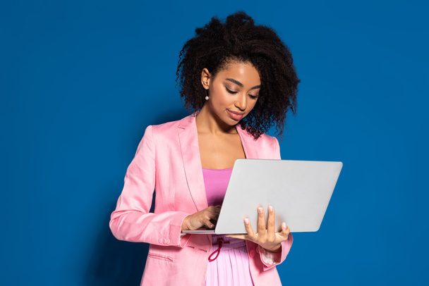 elegant african american businesswoman using laptop on blue background - Photo, Image