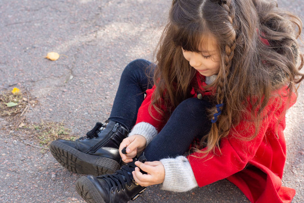 Child's fine motor skills of the hands. Little girl dressing  tying shoelaces. - Фото, изображение