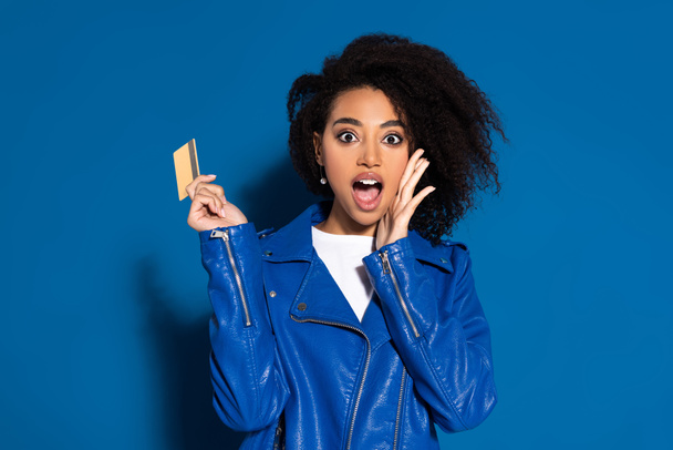 chocado Africano americano mulher com cartão de crédito no fundo azul
 - Foto, Imagem