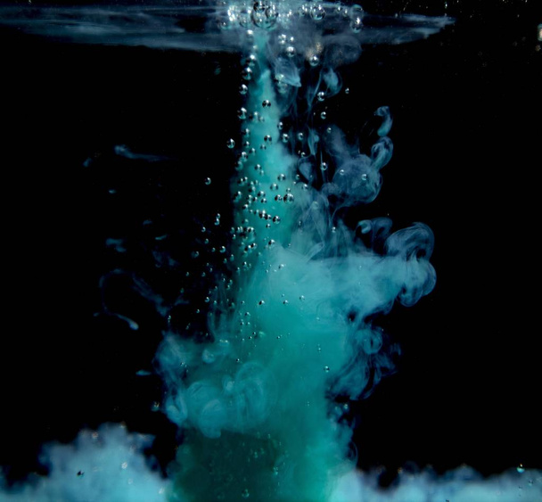 Abstract concept of teal color ink drop plume in water on an isolated  black background - Foto, Imagen