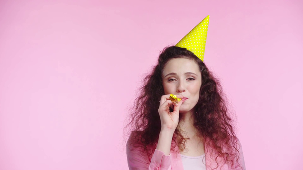 smiling woman blowing in party horn Isolated On pink - Footage, Video