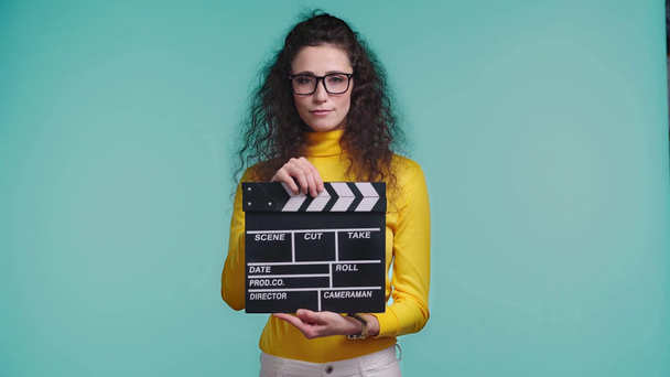 smiling woman using clapboard isolated on turquoise  - Footage, Video