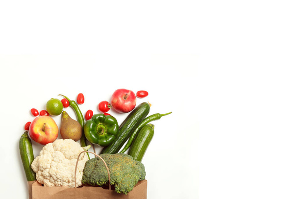 Bolsa de papel de diferentes verduras y frutas agrícolas saludables aisladas sobre un fondo blanco. Vista superior. Piso plano con espacio de copia. - Foto, imagen