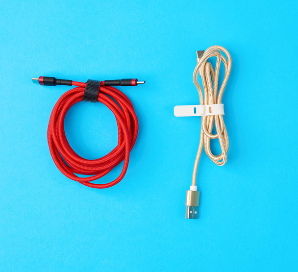 Mobil cihazları kırmızı ve altın renkte şarj etmek için bükülmüş kablo - Fotoğraf, Görsel