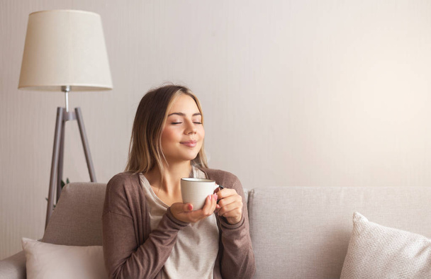Millennial γυναίκα απολαμβάνοντας μυρωδιά του φρέσκου καφέ στο σπίτι - Φωτογραφία, εικόνα