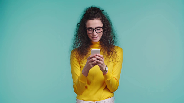 femme souriante utilisant smartphone isolé sur turquoise
  - Séquence, vidéo