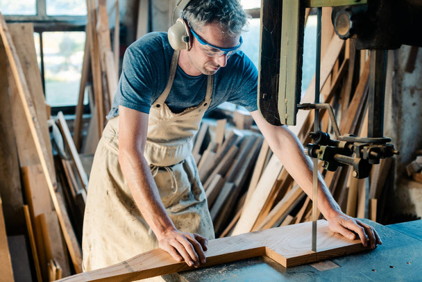 Carpintero en la sierra de banda en su taller de madera
 - Foto, Imagen