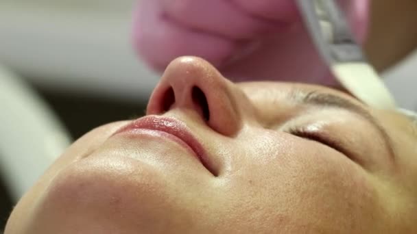 Žena se připravuje na laserovou omlazovací proceduru v salonu. Kosmetolog-dermatolog dokončí zákrok fotorejuvenace. Střelba je z různých úhlů - Záběry, video