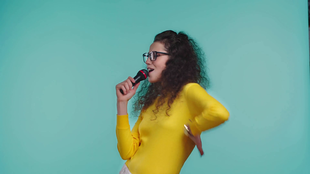χαρούμενη γυναίκα που τραγουδάει με μικρόφωνο απομονωμένη στο τυρκουάζ  - Πλάνα, βίντεο