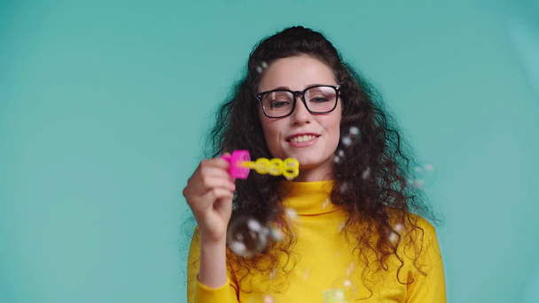 sonriente mujer soplando burbujas de jabón aislado en turquesa
  - Imágenes, Vídeo