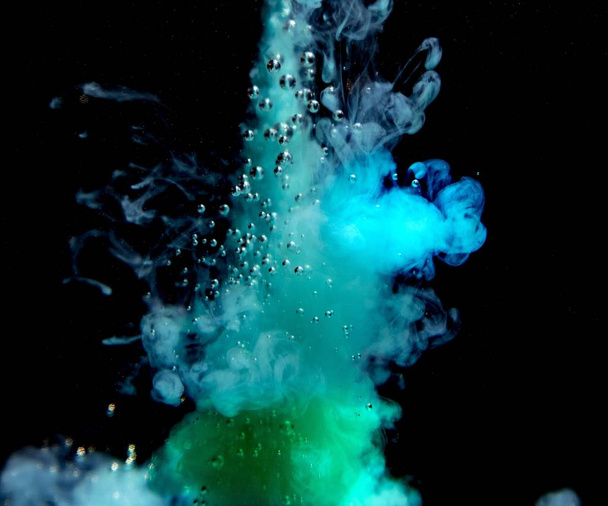 Αφηρημένη έννοια του teal και πράσινο χρώμα μελάνι σταγόνα plume στο νερό σε ένα απομονωμένο μαύρο φόντο - Φωτογραφία, εικόνα