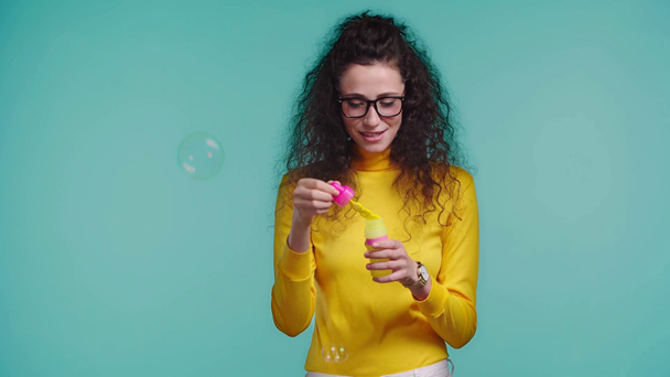 sonriente mujer soplando burbujas de jabón aislado en turquesa
  - Imágenes, Vídeo