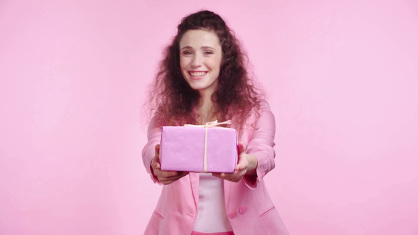 улыбающаяся женщина показывает подарок изолирован на розовый
 - Кадры, видео