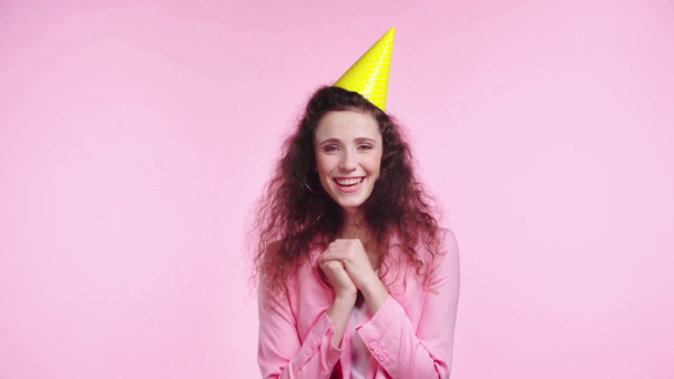 smiling woman with party cap clapping isolated on pink - Felvétel, videó