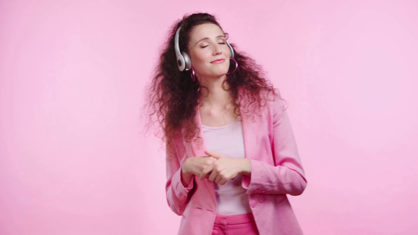uśmiechnięta kobieta ze słuchawkami tańczącymi na różowo - Materiał filmowy, wideo