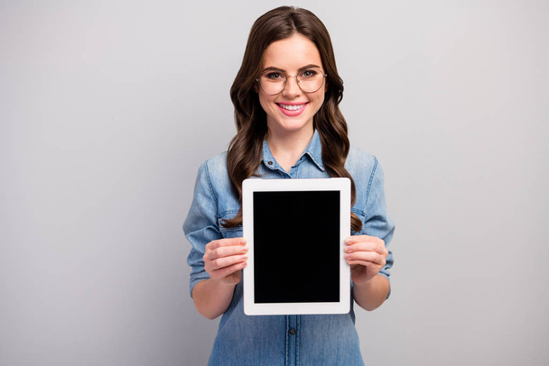Fénykép a gyönyörű szabadúszó hölgy hold e-olvasó tabletta bemutató új modul modell eladás alacsony ár kopás specifikációk alkalmi farmer farmer ing elszigetelt szürke színű háttér - Fotó, kép