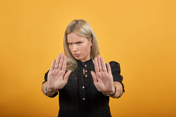 Siyah elbiseli bir kız sinirli bir kadın durağı simgeleyen ellerini gösteriyor. - Fotoğraf, Görsel