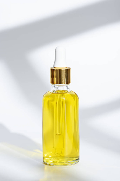 botella de vidrio con pipeta con aceite amarillo cosmético sobre fondo blanco
 - Foto, imagen