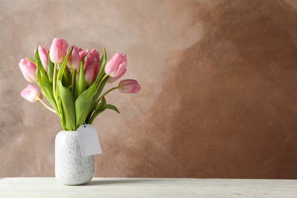Vase with tulips on wooden table, space for text - 写真・画像