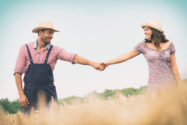 Couple holding hands walking on field wheat - Foto, immagini