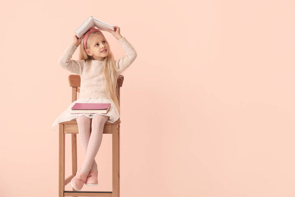 Little girl with books on color background - Valokuva, kuva