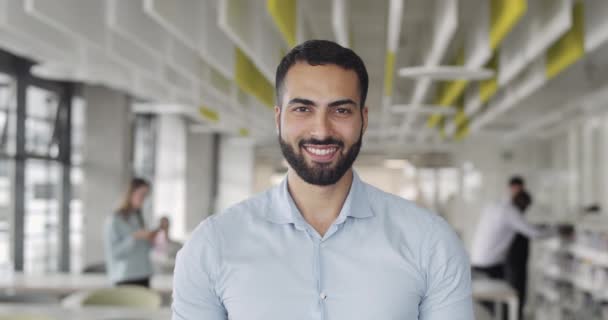 Front view of it trainee looking to camera and smiling at coworking zone. Young startup founder looking happy and standing at office room.Portraits. Concept of work , business, it industry. - Materiał filmowy, wideo