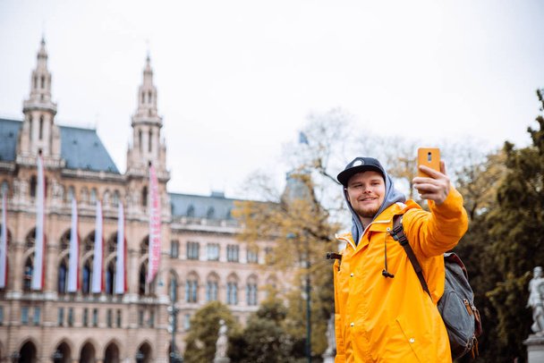 турист-путешественник делает селфи по телефону венской мэрии на заднем плане
 - Фото, изображение
