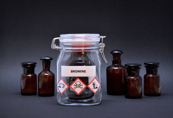Bromine bottle stock images. Toxic liquid stock images. Brown lab bottle. Brown glass container. Phial with warning pictograms on a black background. Laboratory accessories - Photo, Image