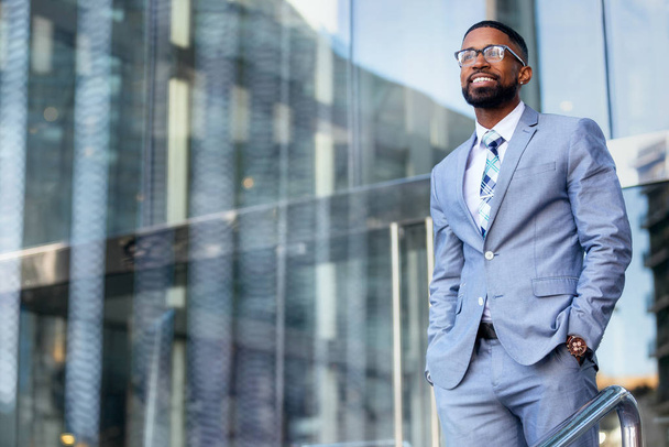 Молодой успешный африканский американский генеральный директор бизнес основатель предприниматель, стильный костюм и очки, уверенно стоящие на рабочем месте офисного здания
 - Фото, изображение