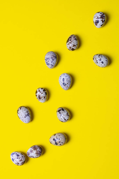 Group of quail eggs on yellow background. Copy space. Top view. Eco organic healthy products. Uncooked small natural fresh eggs. Vertical photo - Valokuva, kuva
