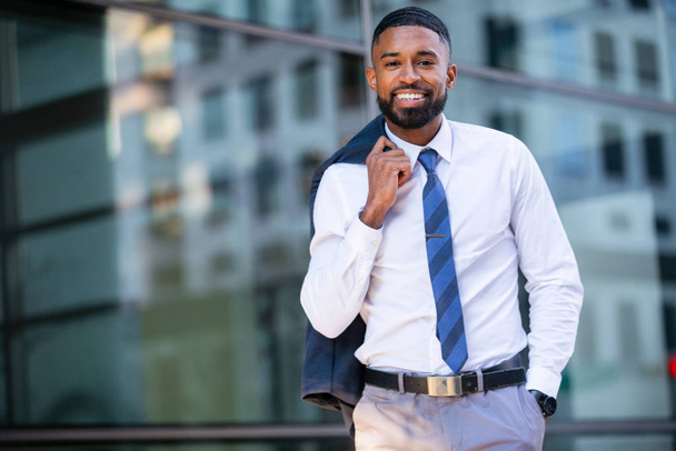 Όμορφο κομψό μοντέρνο κοστούμι, αφροαμερικανός επιχειρηματίας πορτρέτο στο κέντρο της πόλης κτίριο, χαμογελώντας με επιτυχία και επιτυχία - Φωτογραφία, εικόνα