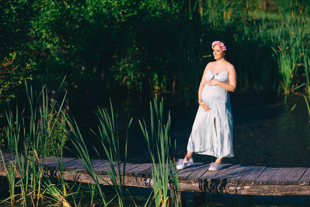 pregnant woman in dress holds hands on tummy and closed eyes on  - Foto, Imagen