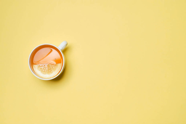 A cup of tea with lemon on a yellow paper background. Top view. - Foto, Imagen